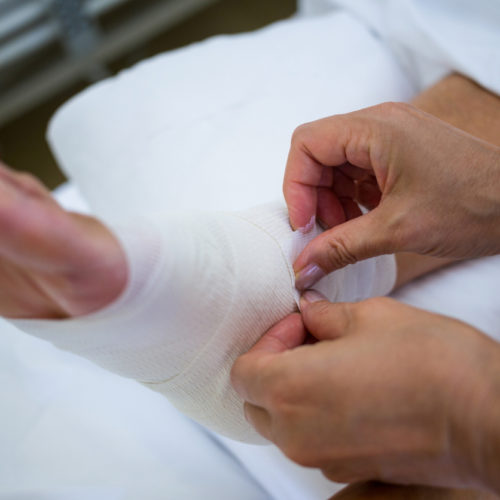 Doctor bandaging patients leg in hospital