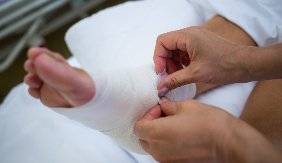 Doctor bandaging patients leg in hospital