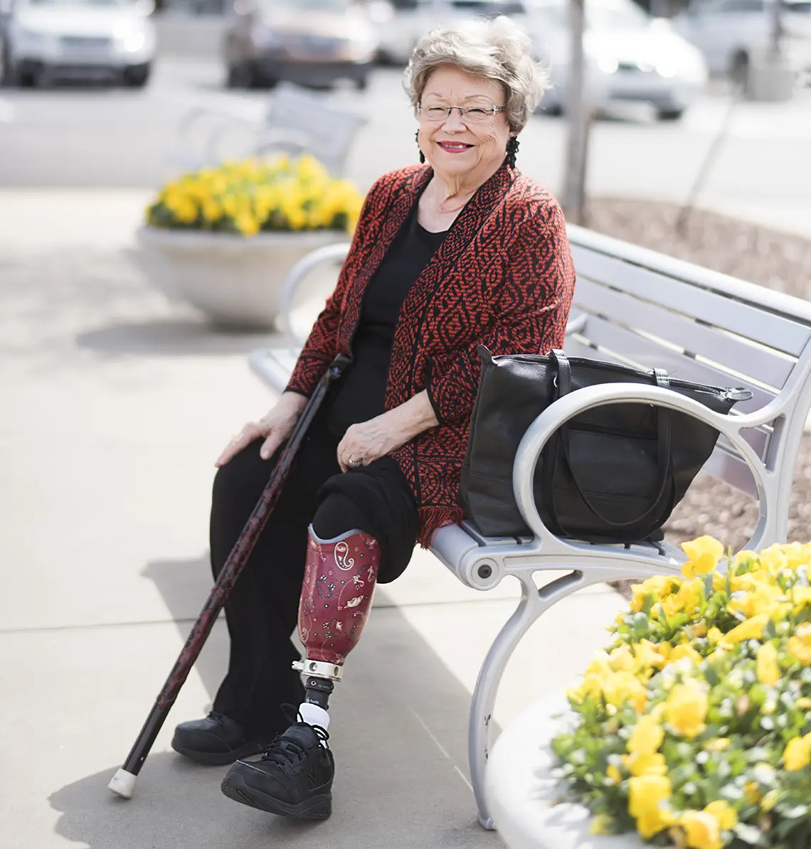 women with a prosthetic leg smiling while sitting on a bench outside