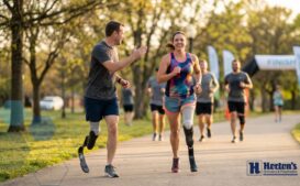 Runner with prosthetic leg crossing finish line at race, demonstrating successful running with prosthetics